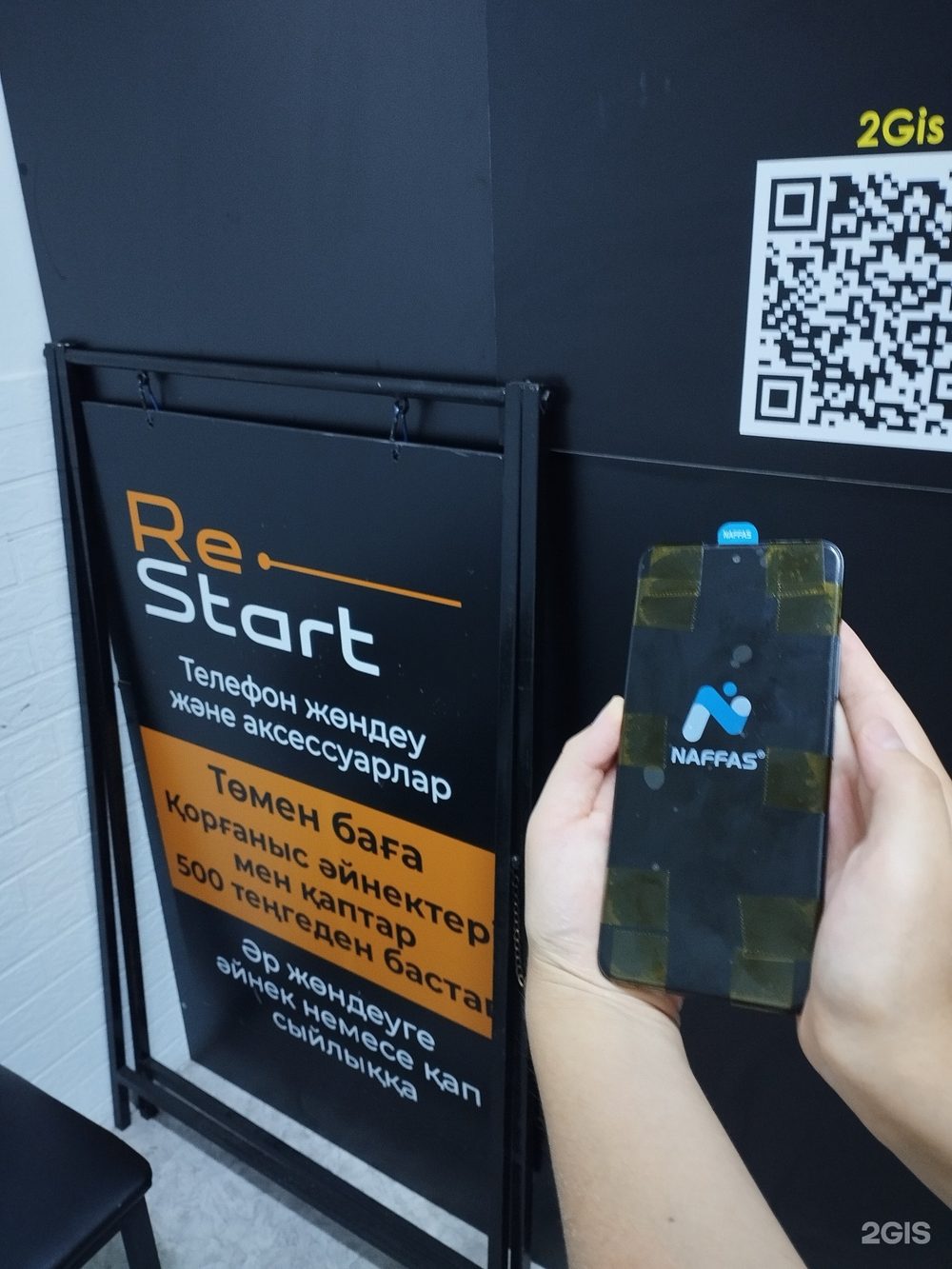 Телефон сразу после ремонта на фоне вывески Re-start